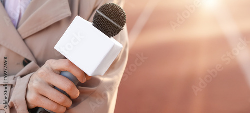 Female reporter with microphone at the stadium, closeup
