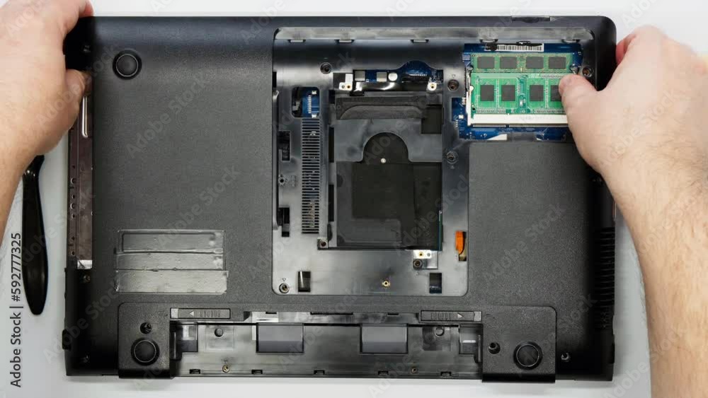 Repairman disassembles laptop. The master removes the cover from the