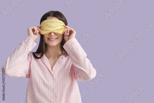 Young woman with sleeping mask on lilac background