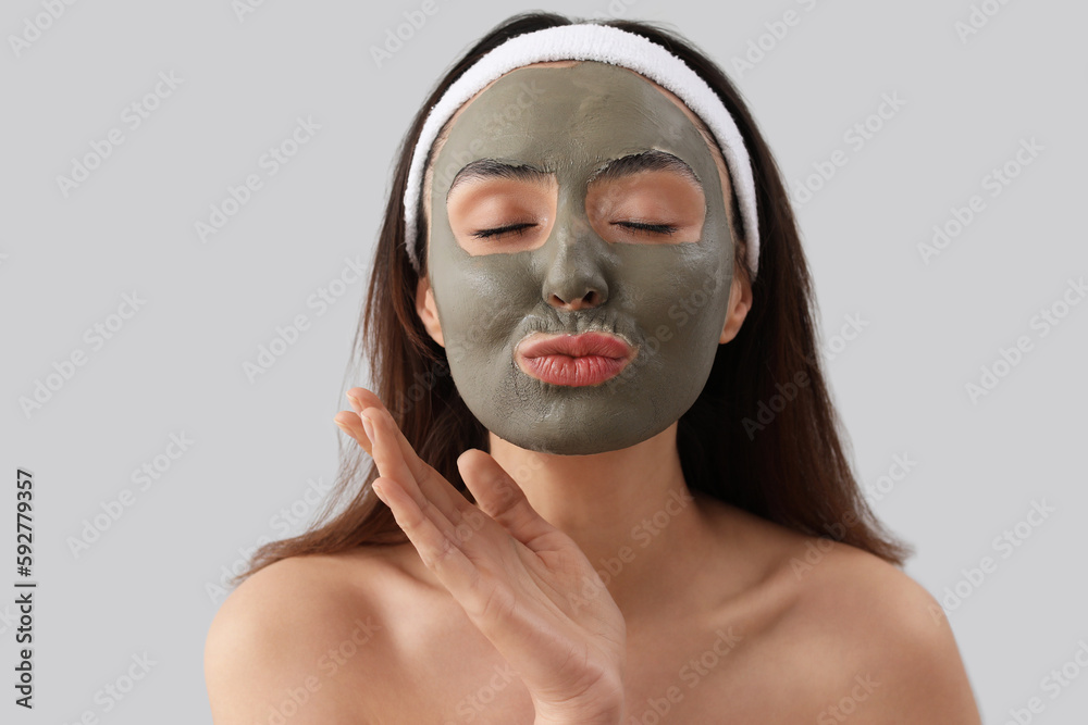 Young woman with applied clay mask blowing kiss on grey background, closeup Young woman with applied clay mask blowing kiss on grey background, closeup