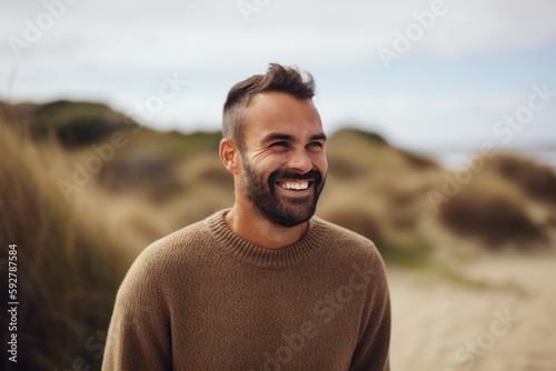 Portrait of a smiling young man standing on the beach at the seaside