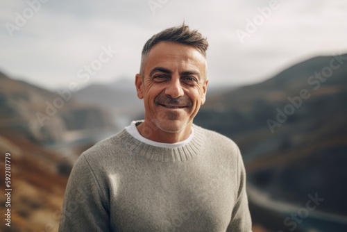 Portrait of a smiling middle-aged man in a sweater on the background of mountains.