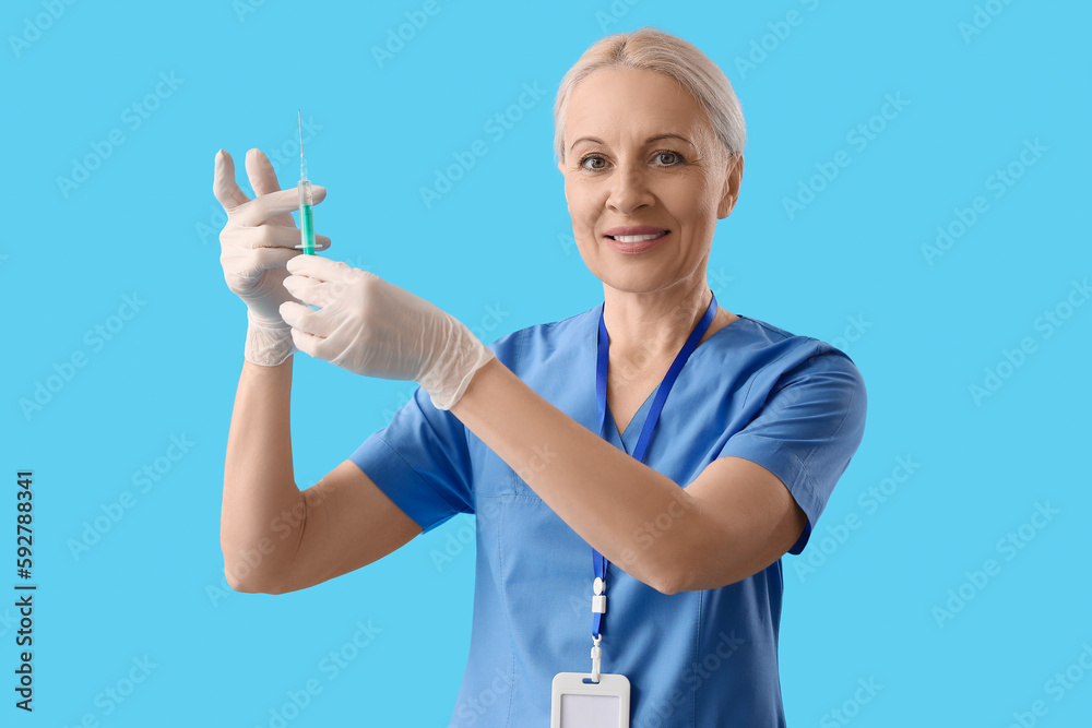 Mature doctor with syringe on blue background Mature doctor with syringe on blue background