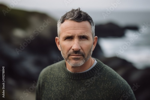 Portrait of handsome mature man standing on the beach by the sea