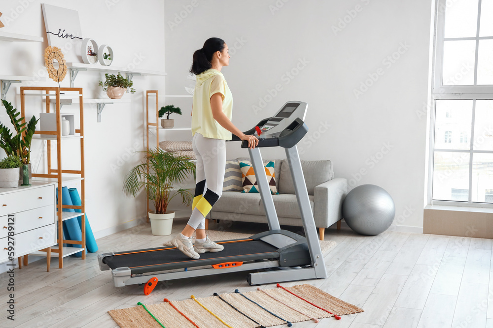 Fototapeta premium Beautiful woman training on treadmill at home