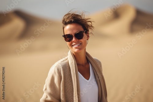 Portrait of beautiful young woman in sunglasses and warm coat standing in the desert