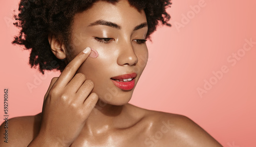 Spa and skincare. African american beauty woman applied scrub, cleansing gel to wash her face, cosmetic product for glowing, nourishing effect, pink studio background photo