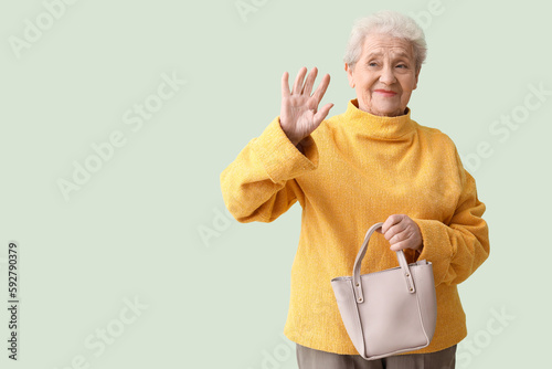 Senior woman with bag wavin...