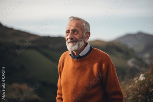Portrait of a senior man in an orange sweater standing in the countryside