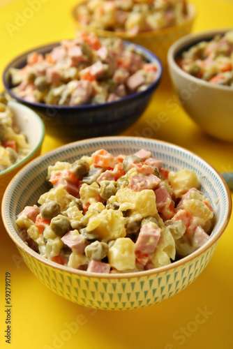 Bowl of tasty Olivier salad on yellow background