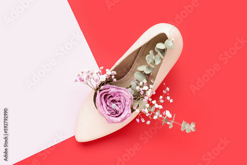 Heel with engagement ring and flowers on color background