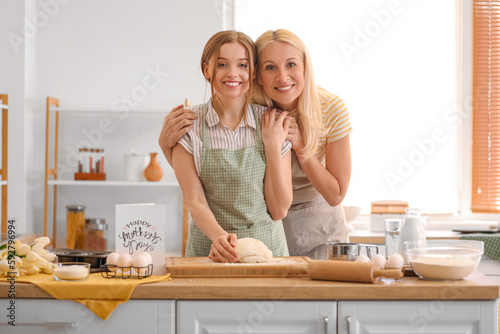 Mature woman with her daughter preparing dough in kitchen. Mother's Day celebration