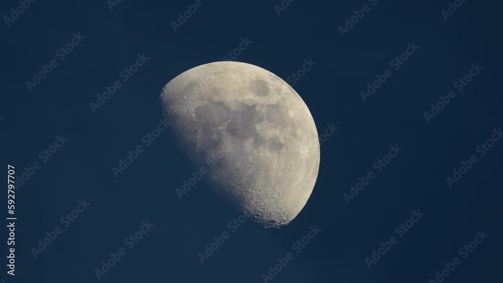 Bright full moon behind fast moving thin layer of clouds on night blue sky