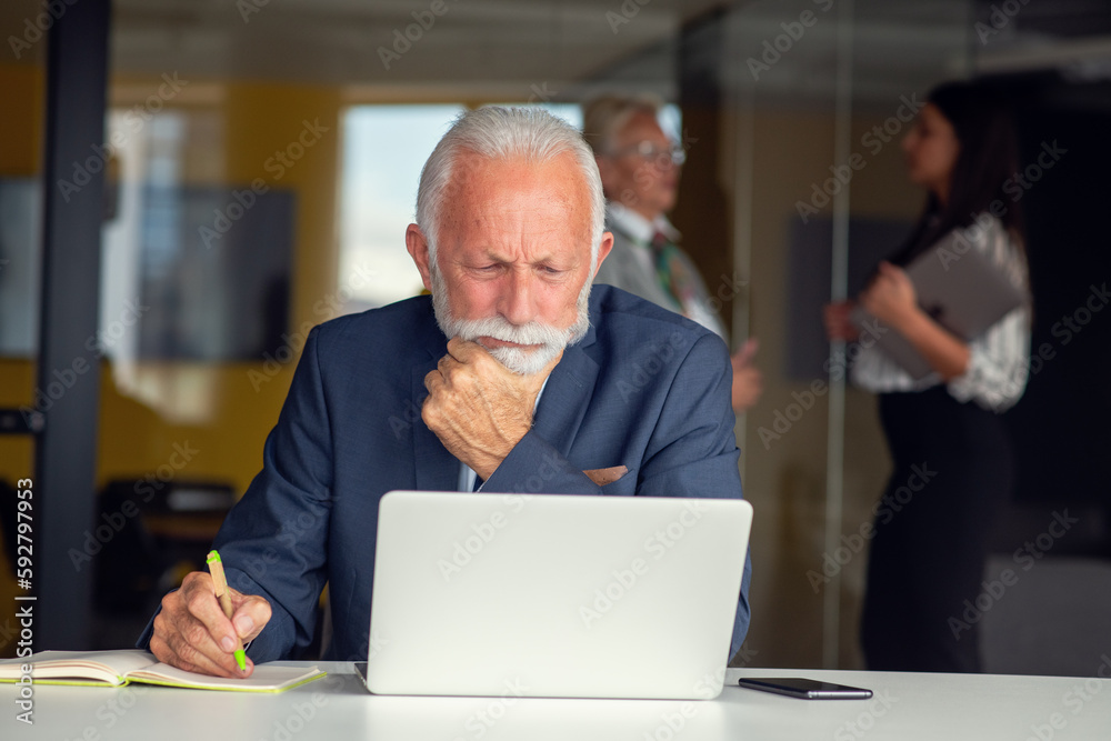 Senior businessman working on laptop computer in modern office Senior businessman working on laptop computer in modern office