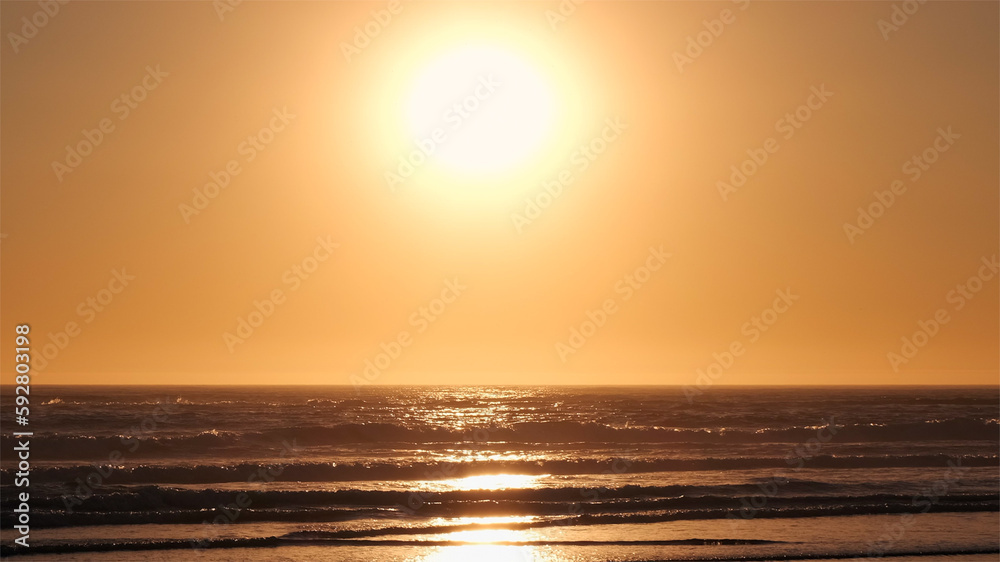 Warm, hazy sunset over the Atlantic ocean on a hot evening in summer. Cloudless sky glowing orange