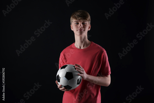 Teenage boy with soccer ball on black background