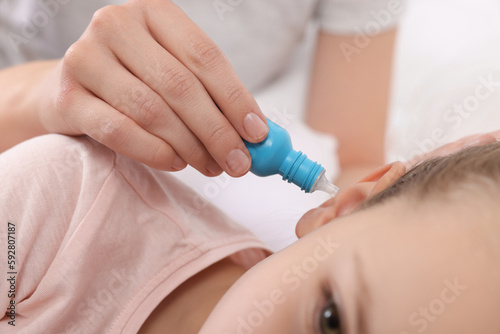Mother dripping medication into daughter's ear, closeup
