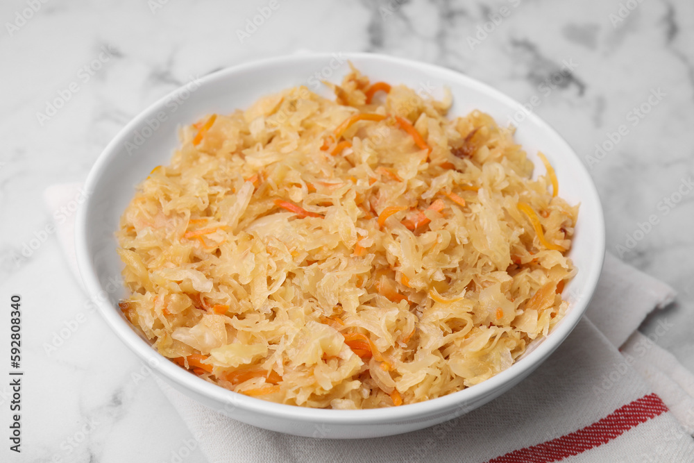 Bowl with tasty sauerkraut on white marble table, closeup