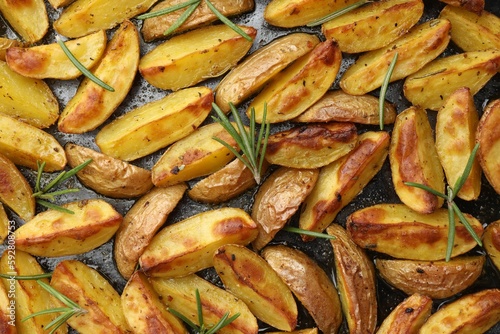 Delicious baked potatoes with rosemary on black surface, flat lay