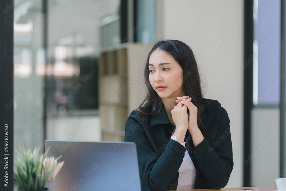 The stressed and exhausted millennial Asian businesswoman is tired after using a laptop while working remotely on a computer at a modern office. The stressed and exhausted millennial Asian businesswoman is tired after using a laptop while working remotely on a computer at a modern office.
