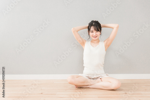 家でストレッチ・柔軟体操をするアジア人女性（脱毛・ヨガ） 