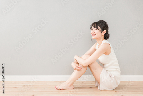 フローリングに座る笑顔の美しいアジア人女性（美容・ダイエット・脱毛） 