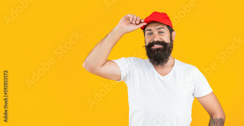 photo of bearded deliveryman with cap, advertisement. bearded deliveryman isolated on yellow.