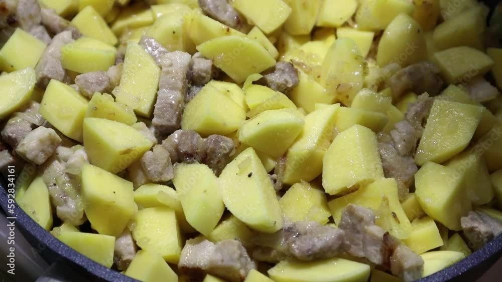Seasoning fried potatoes with pork in a frying pan with fragrant seasoning, close-up Seasoning fried potatoes with pork in a frying pan with fragrant seasoning, close-up