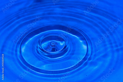 Water drops fall on the blue water surface