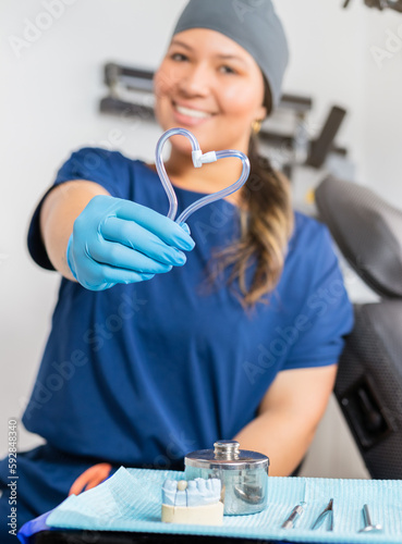 Dentist showcases playful heart shape with two suction tubes photo