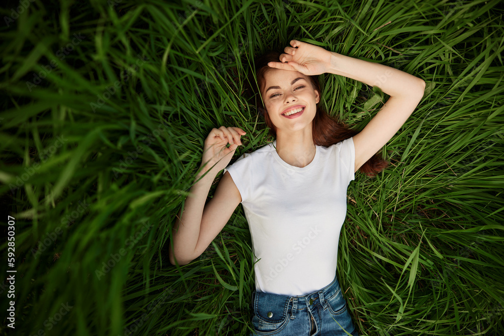 a portrait of a laughing woman with healthy, even teeth lies in the green grass a portrait of a laughing woman with healthy, even teeth lies in the green grass