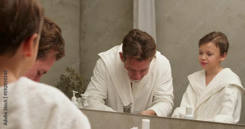 Dad and son washing face after shaving foam on faces in bathroom, spend