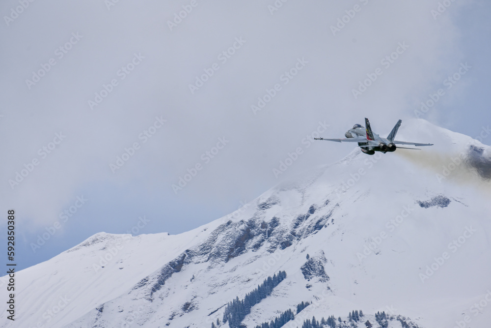 Fighter jet after take of in Swiss alps - snow covered mountains with FA18 - lots of white space, overcast, clouds