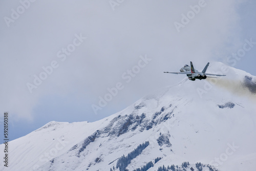 Fighter jet after take of in Swiss alps - snow covered mountains with FA18 - lots of white space, overcast, clouds photo