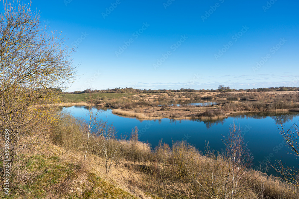 View over a landscape with small hills and lakes created in a closed gravel pit in early spring Denmark