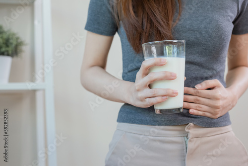 Asian female holding glass milk. resistance deny drinking milk, symptom lactose allergy, concept of health problem, women intolerance ingredient from calcium, stomach ache painful.