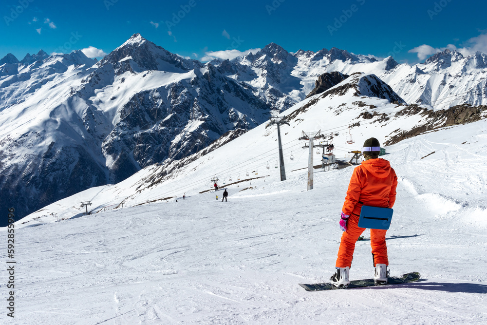 Snowboarder getting ready to roll from the top of a snowy mountain