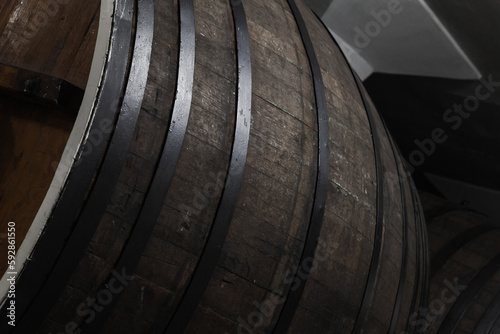 Old brown wooden barrel in dark winery, close-up photo
