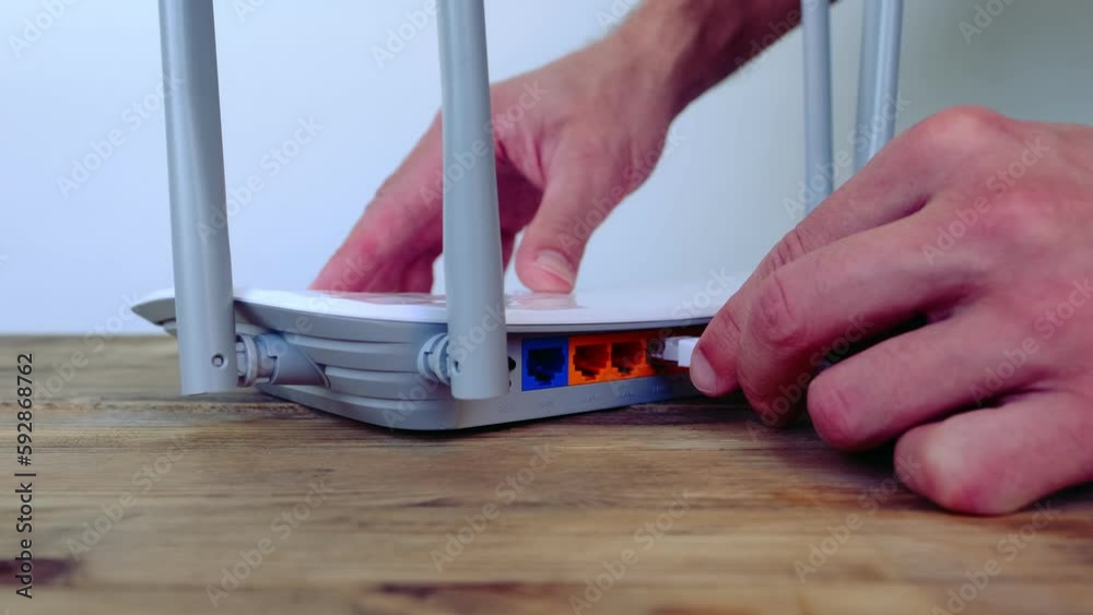 male hands insert white cable into port of Wi-Fi router, modern wireless Router with four non-removable external antennas for better search and signal transmission, concept high speed data processing