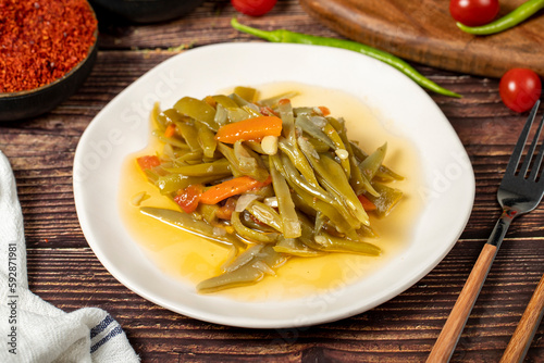 Green bean dish with olive oil on wood background.