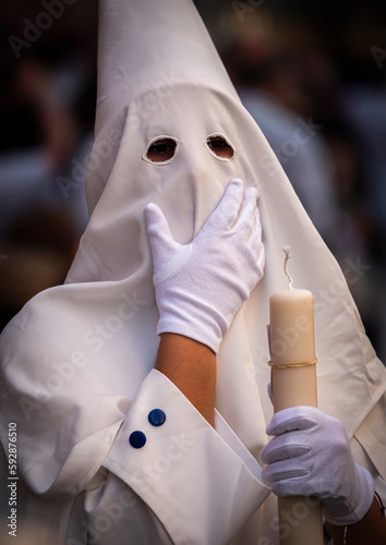 Detail penitent white holding a candle during Holy Week, Spain