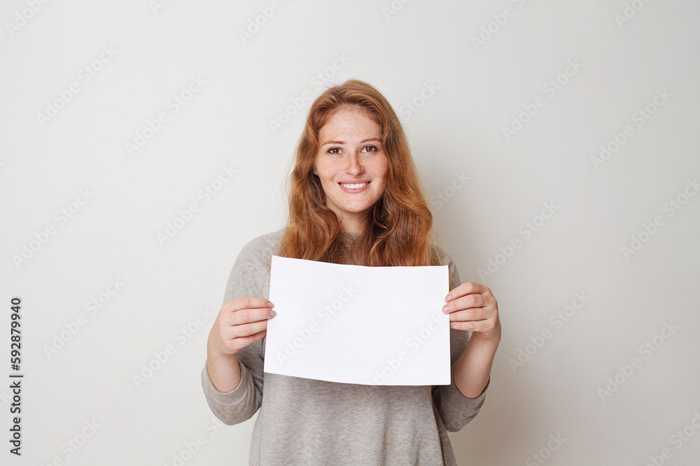 Fototapeta premium Joyful woman with empty blank white board banner against white studio wall background