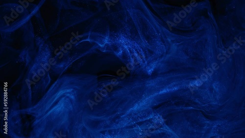 Dark blue paint flowing abstract background. Deep art ink. Shiny blue liquid. Acrylic texture in motion.