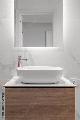 Close-up of an empty bathroom in white tones with a sink with a cabinet and a mirror in a new apartment. The concept of new plumbing and stylish design