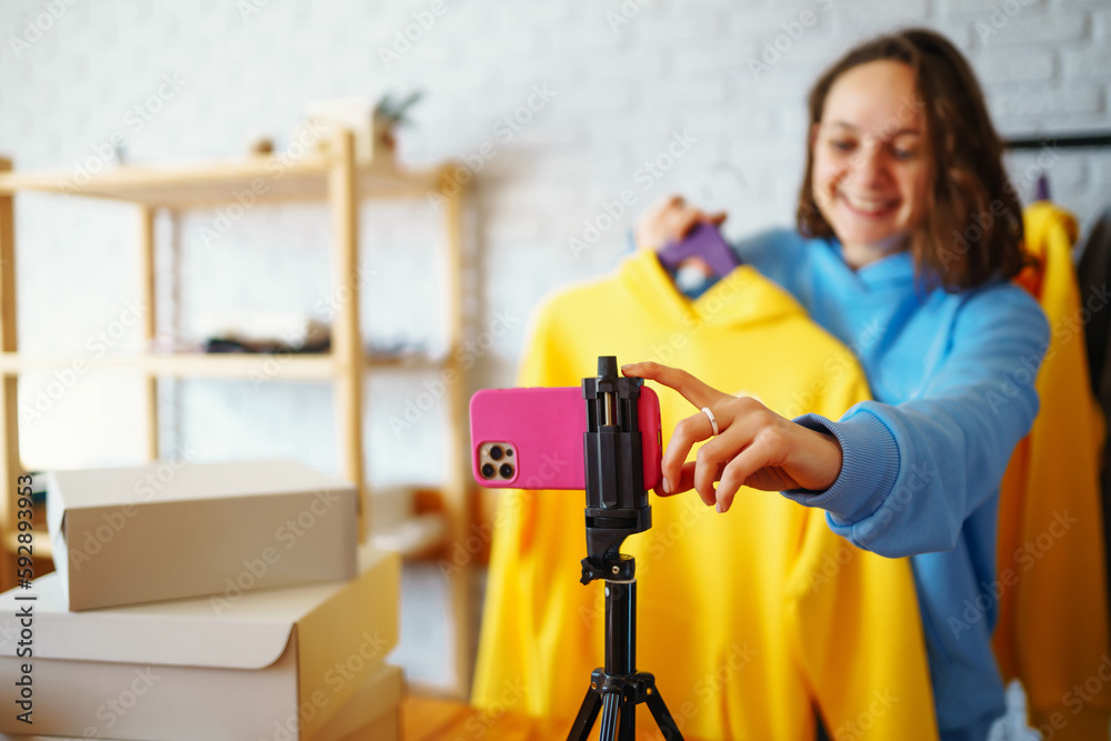 Young owner of an online store is recording live video on preparing parcels for shipping. Woman blogger talking with subscribers, recording video for vlog. Internet marketing and sales. Young owner of an online store is recording live video on preparing parcels for shipping. Woman blogger talking with subscribers, recording video for vlog. Internet marketing and sales.