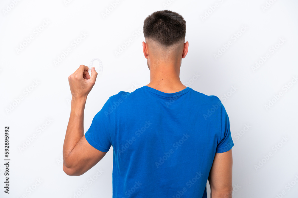 Young caucasian man holding invisible braces isolated on white background in back position Young caucasian man holding invisible braces isolated on white background in back position