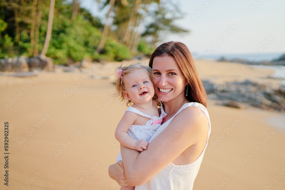 Portrait of happy young mother holding little daughter on the tropical beach. Portrait of happy young mother holding little daughter on the tropical beach.