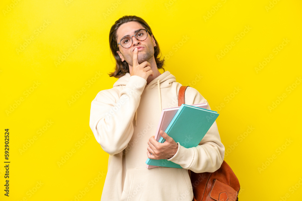 Young student handsome man isolated on yellow background having doubts while looking up Young student handsome man isolated on yellow background having doubts while looking up