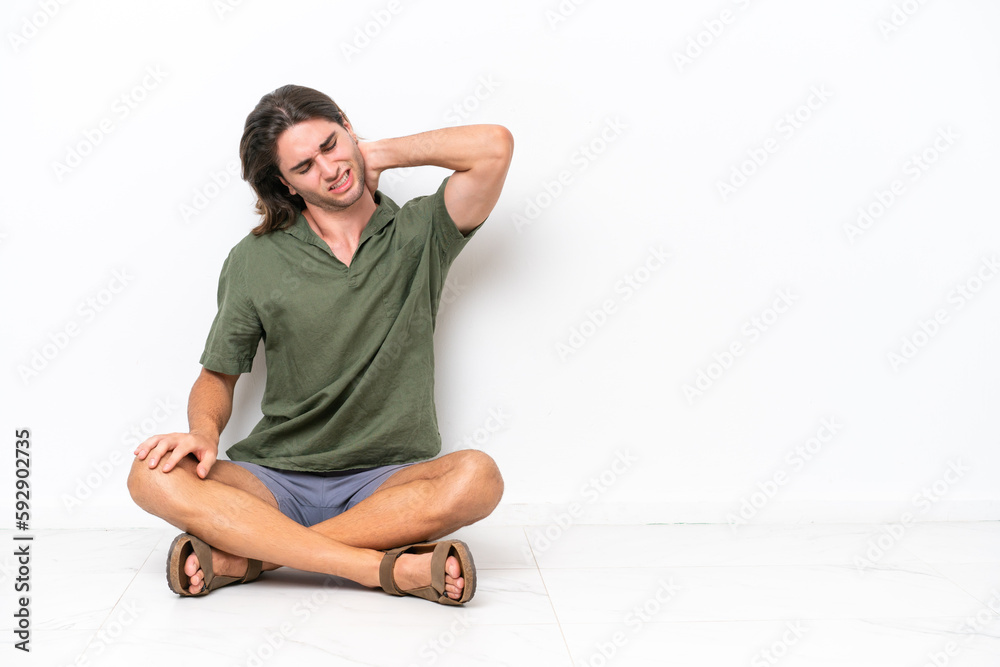 Young handsome man sitting on the floor isolated on white background with neckache Young handsome man sitting on the floor isolated on white background with neckache