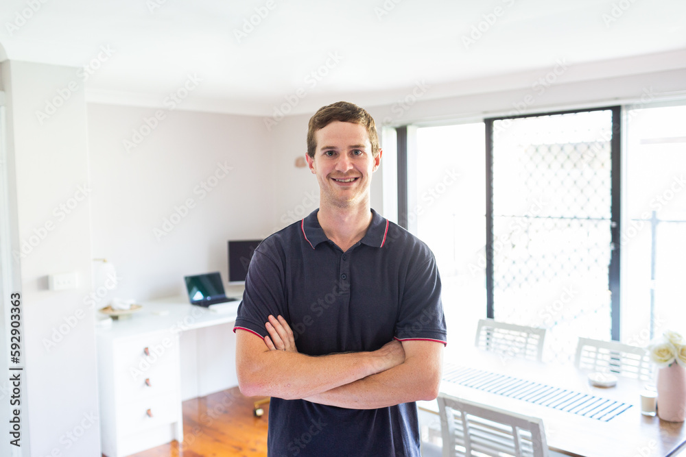 Environmental portrait of young man in his twenties standing with home office behind Environmental portrait of young man in his twenties standing with home office behind